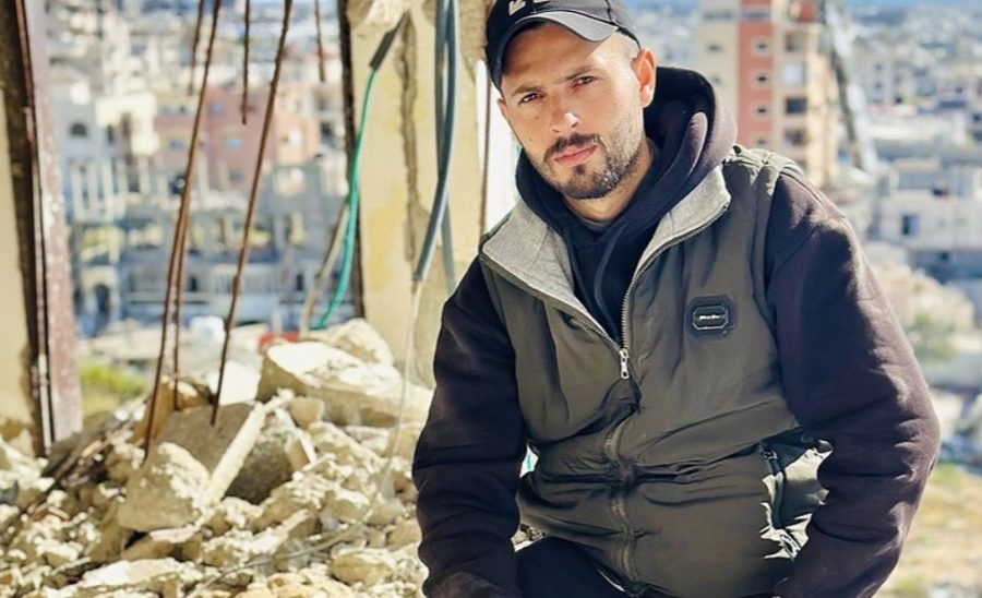 Abdullah crouching among rubble
