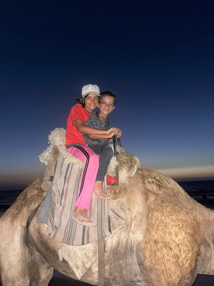 Two children on a camel at dusk