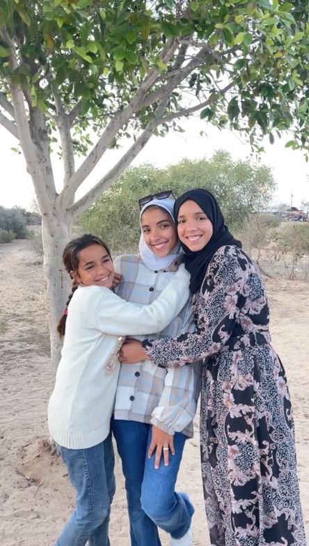 Three girls from the family standing by a tree