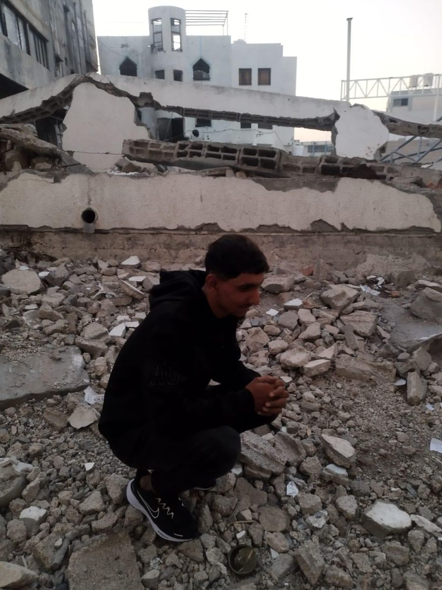 Tareq crouching among rubble