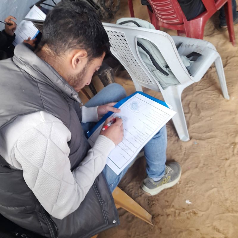 A young man filling in a form while seated in a tent